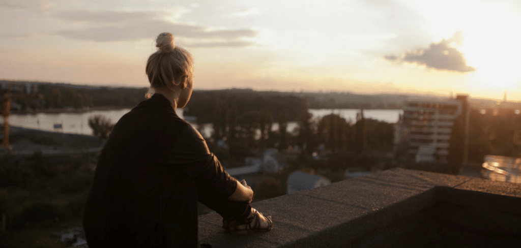 Nainen katsomassa auringonlaskua kiinteistön katolla.